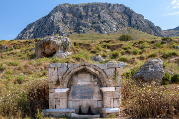 Medieval stone fountain at the base of Acrocorinth hill, in Ancient Corinth, Greece. It was built in 1515 and has ottoman inscription on it.