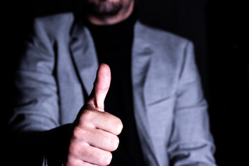 Businessman giving thumbs up in the dark