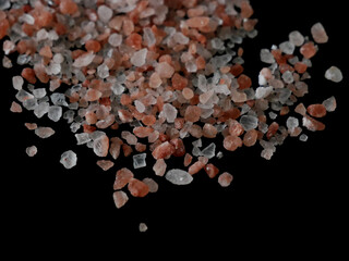Coarse pink himalayan salt crystals isolated on black background close up