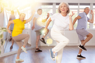 Cheerful elderly woman attending group choreography class, learning modern dynamic dances. Concept...