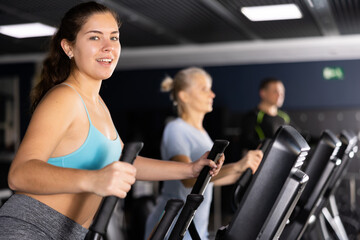 Fototapeta na wymiar Fit young woman working out at elliptical machine in gym