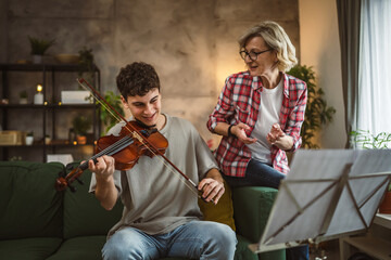 Young man learn how to play violin under instruction mature professor