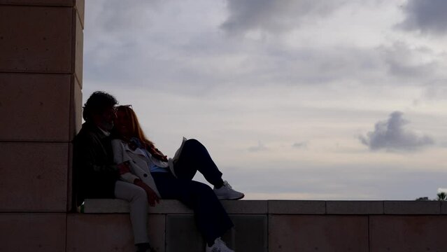 Silhouette of romantic senior couple embracing and bonding together. Copy space in dramatic sky. Valentine and romance concept