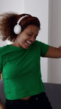 Young african ethnicity woman having fun alone dancing in living room. Millennial mixed race female celebrating enjoying free time at home. Vertical HD screen footage.