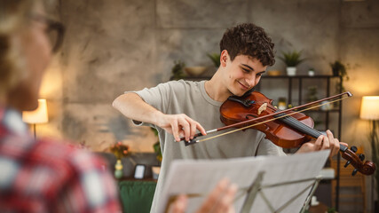 Young man learn how to play violin under instruction mature professor