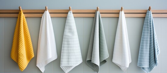 A row of five colorful towels of different sizes hanging neatly on a wooden rail in a bathroom