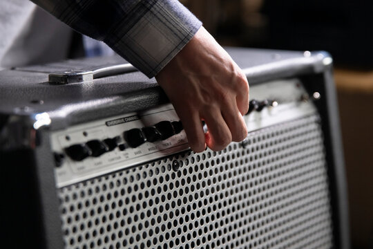 Guitarist Fine-Tunes Amplifier Settings Before a Performance in a Backstage Area