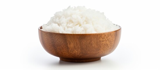 A wooden mixing bowl filled with staple food ingredient white rice, displayed on a plain white tableware background, ready to be used in a delicious cuisine recipe