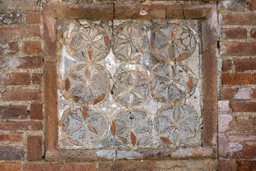 Part of a roman wall ornate with flowers made out of stone and brick