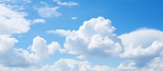 Obraz premium A serene natural landscape with a sky filled with fluffy white cumulus clouds against an electric blue backdrop, creating a peaceful meteorological event in the horizon