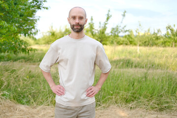 Satisfied young man 30-35 years old in light t-shirt, stylish glasses against natural background,...