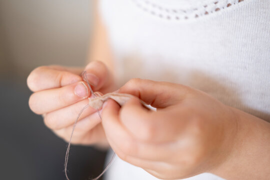 little girl's hands holding needle and fabric, showing focus while learning to sew clothes for doll, fine motor skills, sensory experience, preschool education