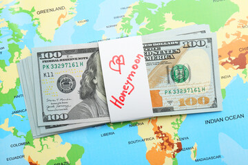 Stack of money with word Honeymoon on world map, top view