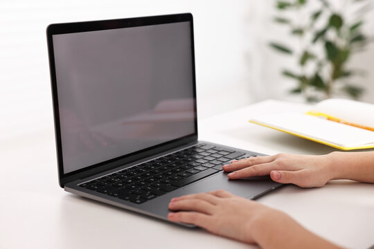E-learning. Girl using laptop during online lesson at table indoors, closeup