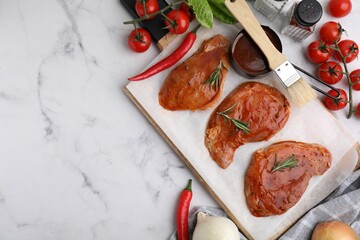 Flat lay composition with raw marinated meat, rosemary, basting brush and products on white marble...