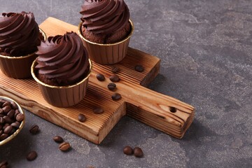 Delicious chocolate cupcakes and coffee beans on grey textured table, closeup. Space for text