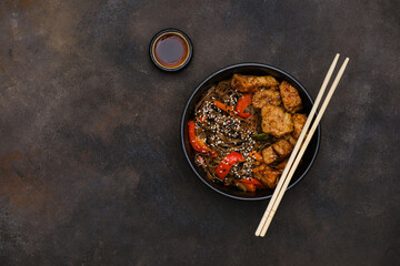 Fried Udon with Chicken and vegetables on dark brown background. Top view. Asian food.