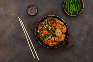 Fried Udon with Chicken and vegetables and green lettuce on dark brown background. Top view. Asian food.