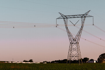 power towers passing with their cables over agricultural fields at dusk