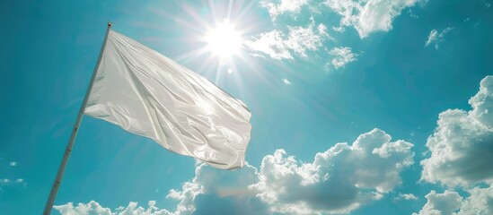 A white flag flutters on a flagpole under a sunny sky with clouds, seen in close-up.