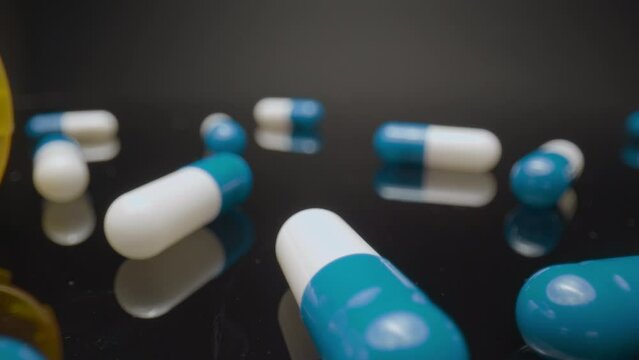 Spilled Pill Bottle, Macro Pan. Macro wide angle extreme close up (ECU) panning across some scattered blue and white pill capsules.