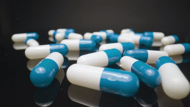 Macro Pills Flyover. Macro wide angle extreme close up (ECU) floating above some scattered blue and white pill capsules.