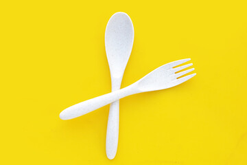Spoon and fork on yellow background.
