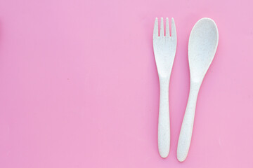 Spoon and fork on pink background.