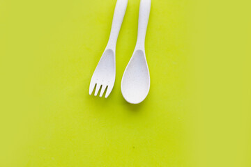 Spoon and fork on green background.