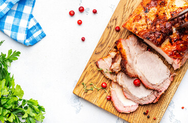 Baked festive pork sirloin with spices and cranberries for sauce, served and sliced on wooden cutting board, white table background, top view