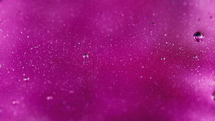 Shimmering gel. Oil bubbles. Defocused neon pink purple transparent smooth glitter spill spreading art abstract background.
