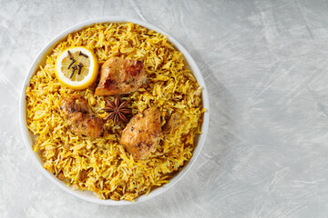 Indian Chicken Biryani with Basmati Rice, Star Anise, Cloves and Lemon on White Plate, Copy Space, Top View