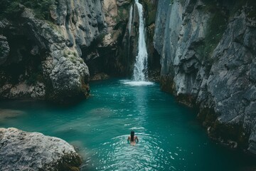 Naklejka na ściany i meble Girl relaxing in water under a tropical waterfall