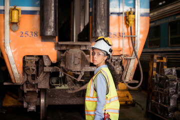 Portrait of railway technician worker in safety vest and helmet working with blueprint at train repair station