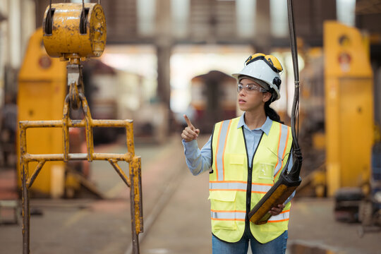 Portrait of railway technician worker in safety vest and helmet working at train repair station