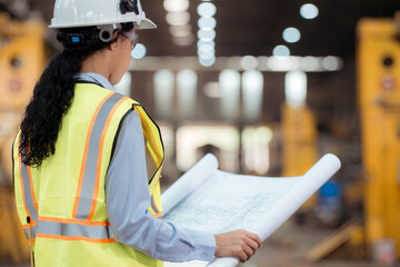 Portrait of railway technician worker in safety vest and helmet working with blueprint at train repair station