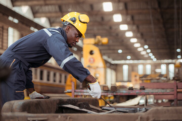 Railway technician in uniform and safety helmet working on train repair station