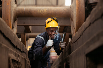 Railway technician in uniform and helmet inspect the train wheels removed from the locomotives in the train workshop.