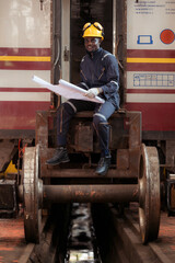Railway technician in uniform and helmet inspect the train wheels removed from the locomotives in the train workshop.