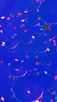 Vertical video. Abstract background. Shimmering mix. Magic liquid. Glowing sequins particles floating on vivid blue glitter texture ink fluid surface with smooth oil bubbles motion.