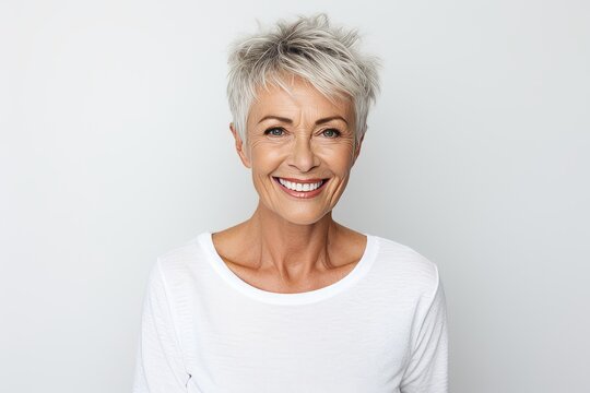Mature woman with short grey hair smiling and looking at camera.