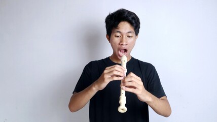 Young Asian man happy and active gesturing playing the flute