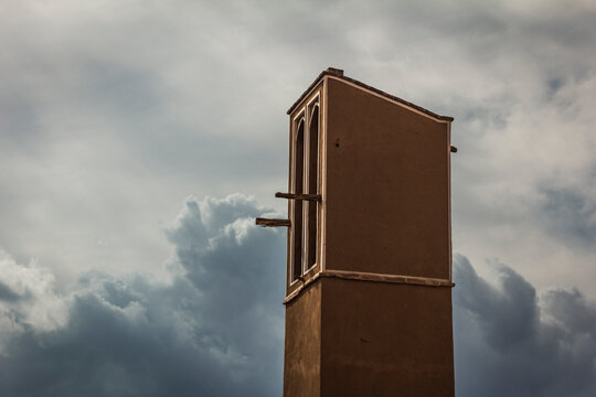 A wind catching tower or ventilation tower made of adobes in Yazd, Iran with a cloudy sky in the background
