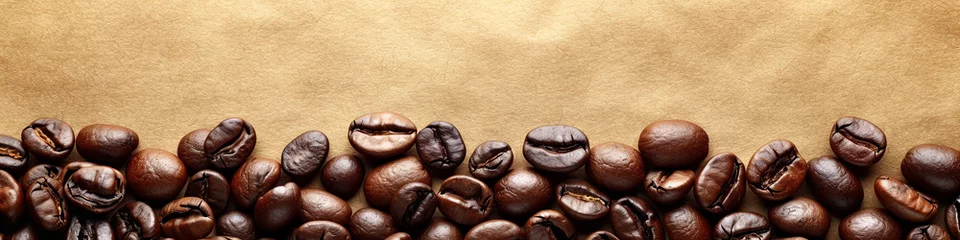  A close up of coffee beans on a brown background. The beans are of different sizes and are scattered across the image © Дмитрий Симаков