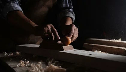 Cercles muraux Ancien avion Carpenter's hands planing a plank of wood with a hand plane, in factory, old, dark 