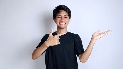 young asian man smiling gesturing right hand pointing left palm