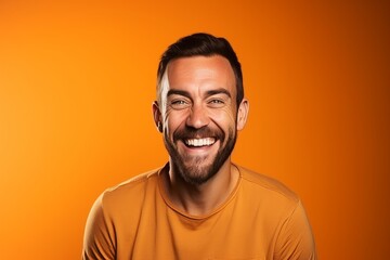 Portrait of a handsome man laughing and looking at camera on orange background - obrazy, fototapety, plakaty