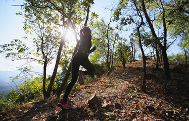 Fitness asian woman running on trail at sunrise tropical forest in winter