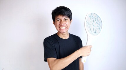 young Asian man using mosquito swatter, electric net racket