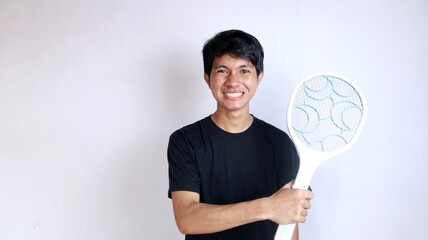 young Asian man using mosquito swatter, electric net racket